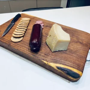 wooden chopping board with biscuits, sliced meat, cheese, and a knife on top of it