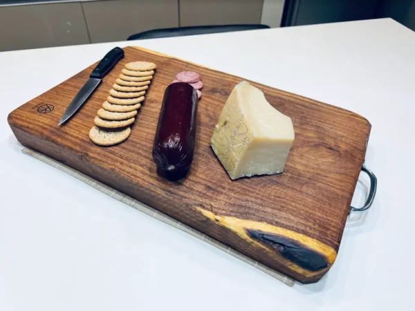 wooden chopping board with biscuits, sliced meat, cheese, and a knife on top of it